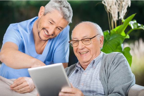 adult son helping senior father tablet home